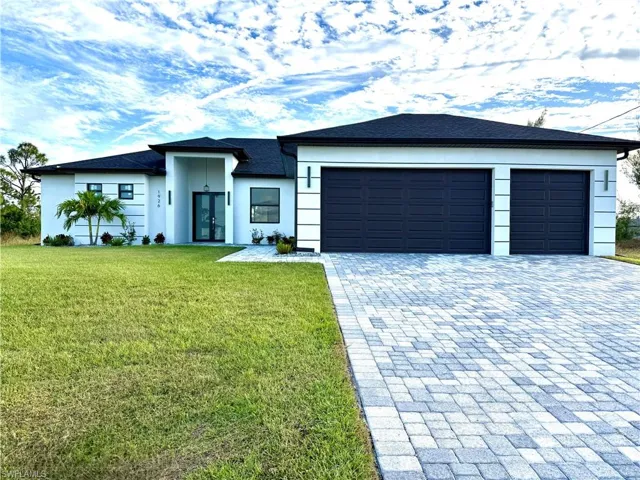 View of front of property with decorative driveway, a front yard, a shingled roof, a garage, and stucco siding