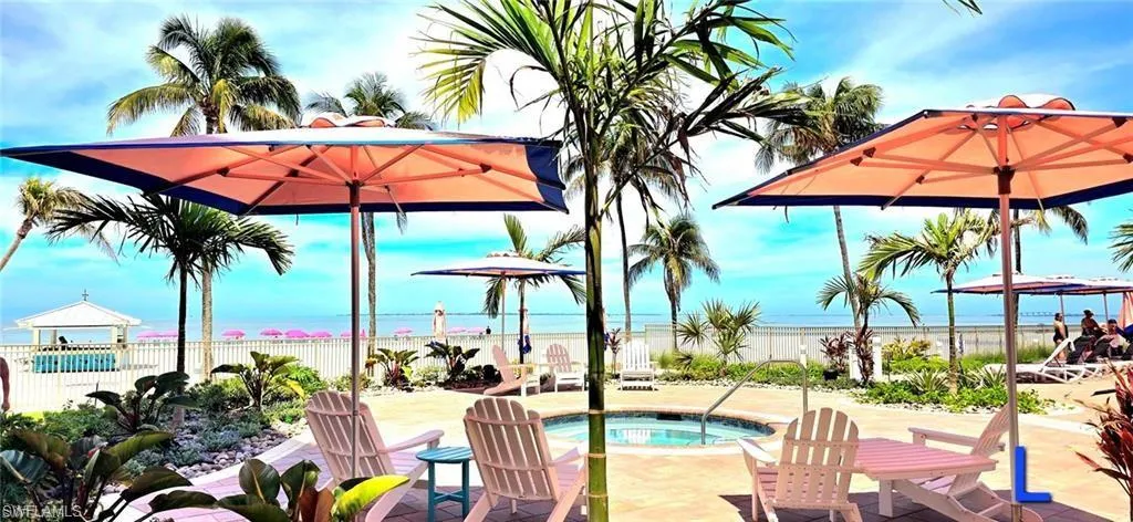 View of swimming pool with a community hot tub, view of water and beach, and a patio