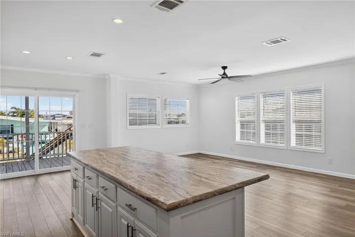 Kitchen featuring a kitchen island, LVP floors, open floor plan, healthy amount of natural light, recessed lighting and sliding glass doors to front porch