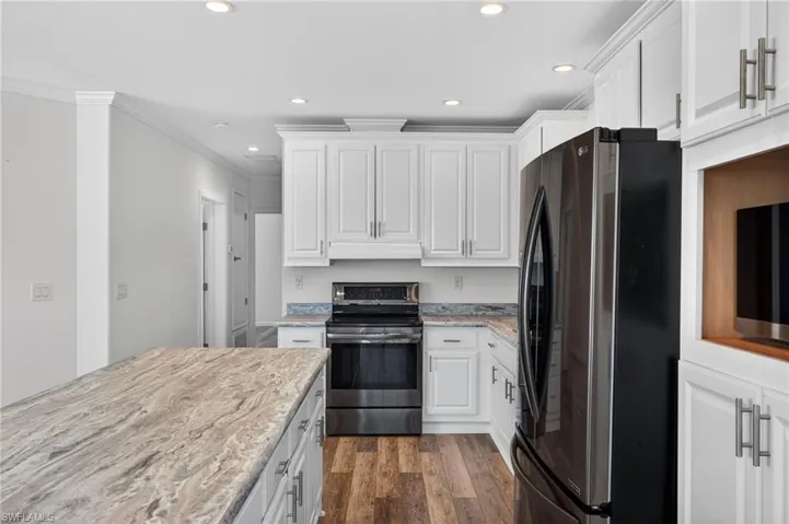 Kitchen featuring stainless steel appliances, white cabinets, LVP floors, recessed lighting, and light counters