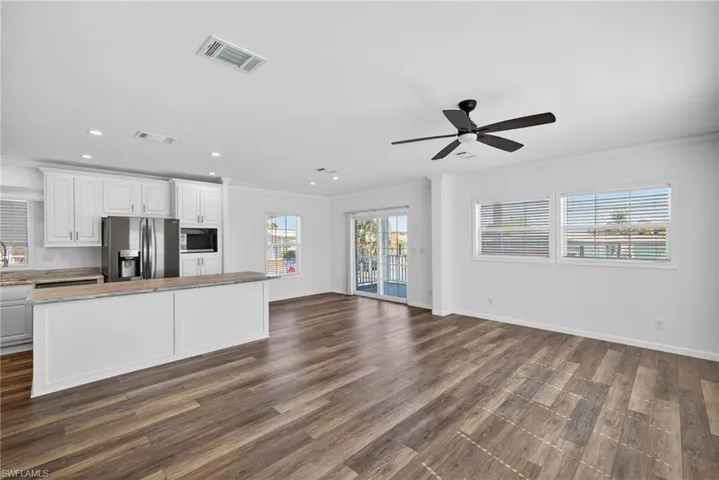 Kitchen featuring white cabinetry, open floor plan, stainless steel refrigerator with ice dispenser, LVP floors, and a ceiling fan