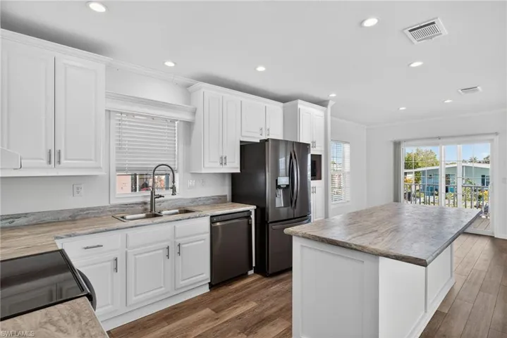 Kitchen with white cabinets, a kitchen island, LVP flooring, light countertops, and crown molding