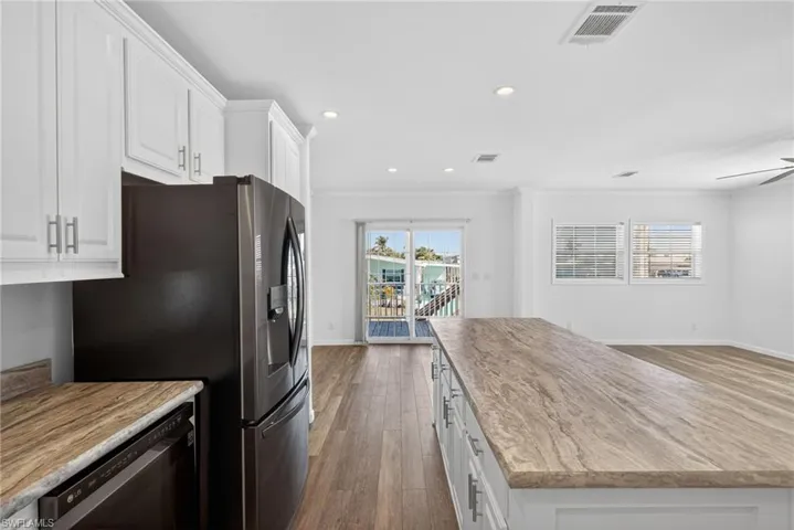 Kitchen with white cabinetry, a kitchen island, dishwasher, recessed lighting, and LVP flooring
