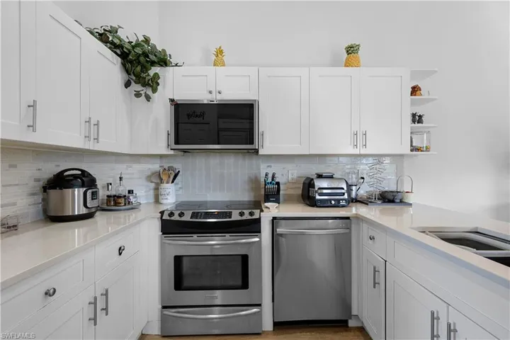 Kitchen featuring white cabinets, appliances with stainless steel finishes, and tasteful backsplash