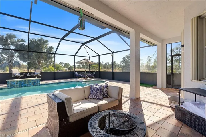 View of patio with a lanai, a fire pit, and a fenced in pool