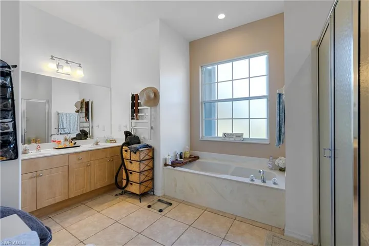 Bathroom featuring tile patterned floors, vanity, and shower with separate bathtub