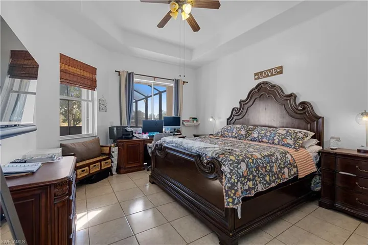 Tiled bedroom featuring a tray ceiling and ceiling fan