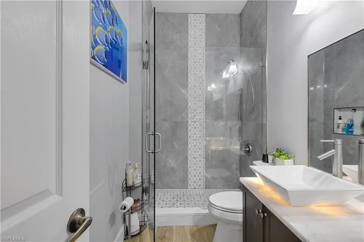 Bathroom featuring toilet, wood-type flooring, a shower with shower door, and vanity
