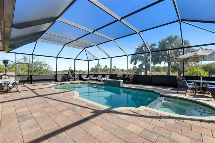 View of swimming pool featuring glass enclosure, an in ground hot tub, and a patio