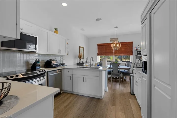 Kitchen featuring kitchen peninsula, stainless steel appliances, white cabinets, and sink