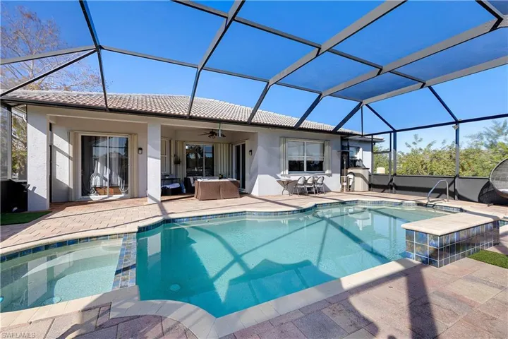 View of pool with a patio, glass enclosure, and ceiling fan
