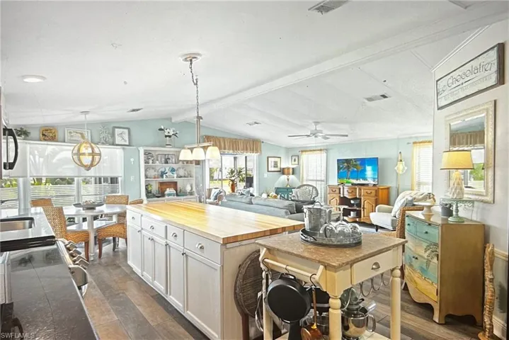 Kitchen featuring lofted ceiling with beams, hanging light fixtures, a kitchen island, and white cabinets