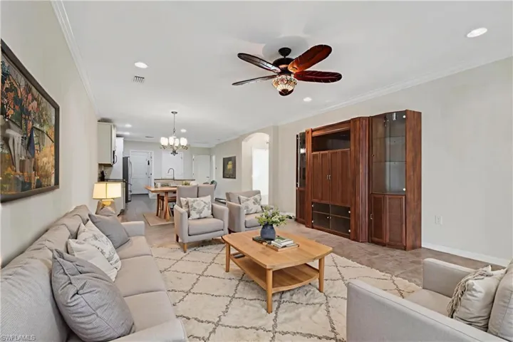 Living room with a chandelier, recessed lighting, arched walkways, crown molding, and ceiling fan