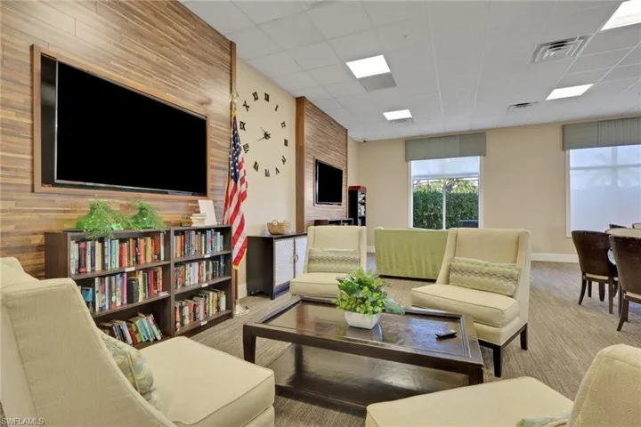 Living room with a paneled ceiling, an accent wall, and carpet