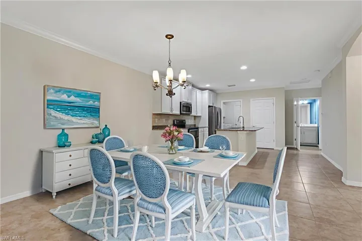 Dining space with crown molding, a chandelier, recessed lighting, and light tile patterned floors
