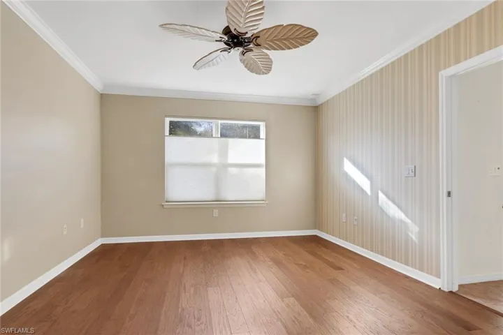 Unfurnished room featuring ornamental molding, hardwood / wood-style flooring, a ceiling fan, and wallpapered walls