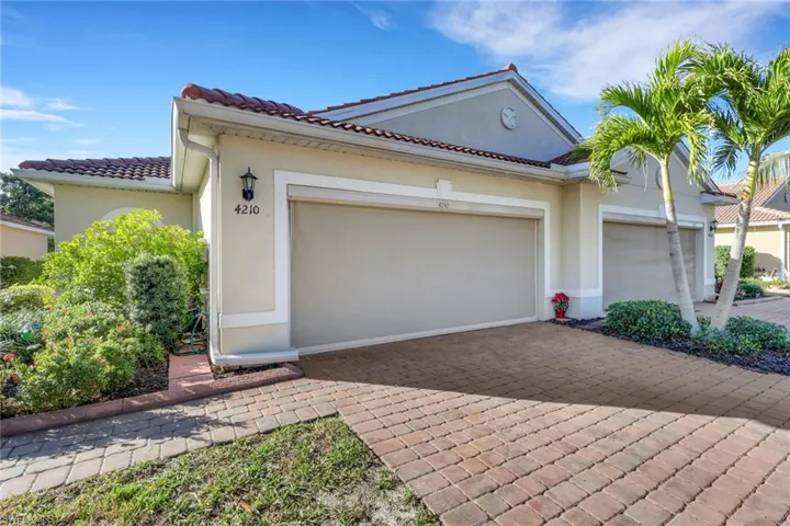 View of front of property featuring stucco siding, decorative driveway, a tiled roof, and an attached garage