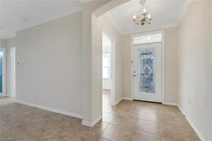 Foyer entrance featuring ornamental molding, arched walkways, a chandelier, and light tile patterned floors