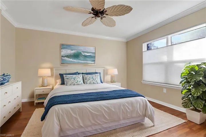 Bedroom featuring crown molding, dark wood-style floors, and ceiling fan