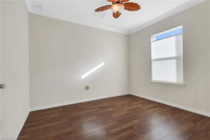 Unfurnished room featuring ornamental molding, dark wood-style flooring, and a ceiling fan