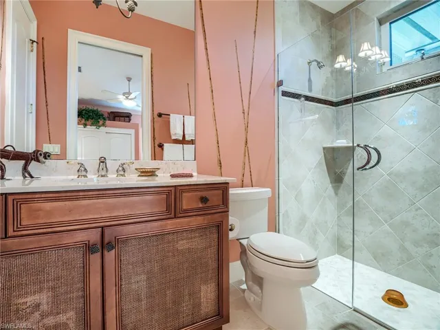 Bathroom with ceiling fan, an enclosed glass shower, tile floors, toilet, and large vanity