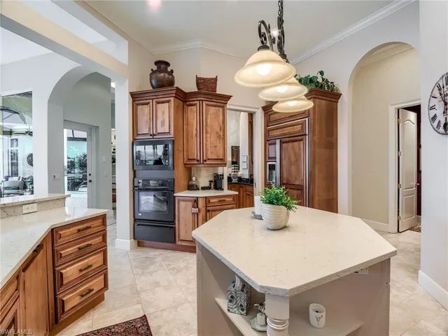 Kitchen featuring pendant lighting, black appliances, a kitchen island, backsplash, and light tile floors