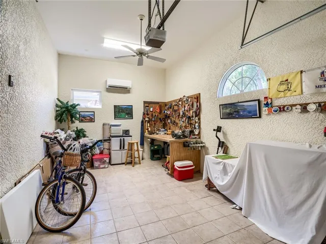 Single car garage featuring ceiling fan, tile floors, and a wall mounted air conditioner