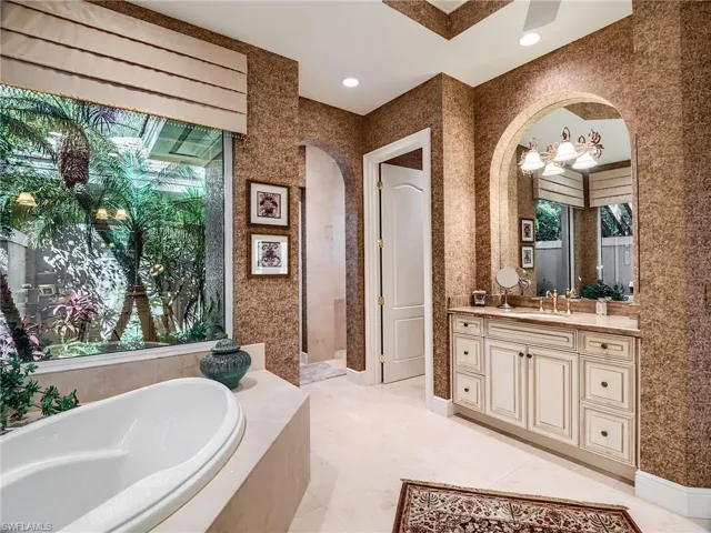 Bathroom with tile flooring, tiled tub, and dual vanities