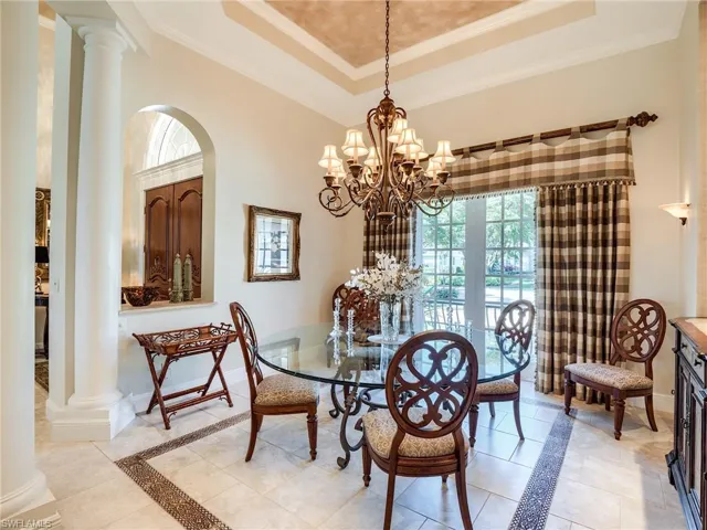 Dining area featuring an inviting chandelier, a tray ceiling, and light tile flooring