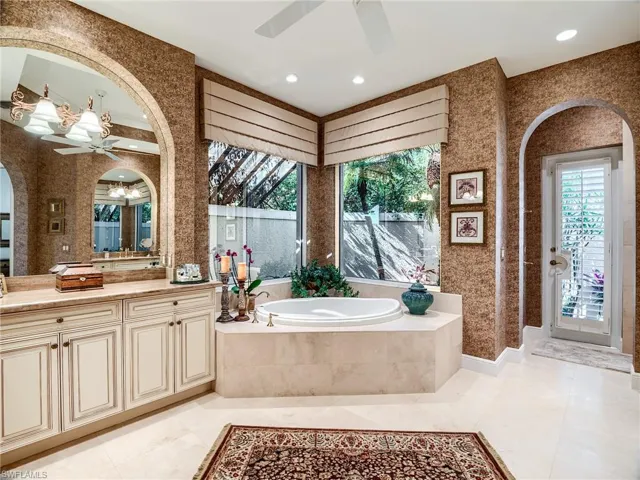 Bathroom with dual vanities, a relaxing tiled bath, tile flooring, and ceiling fan