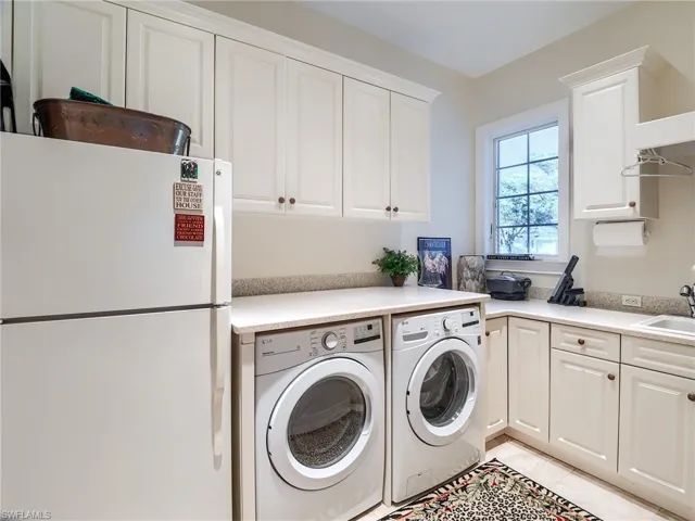 Laundry area featuring light tile floors, sink, cabinets, and washer and dryer