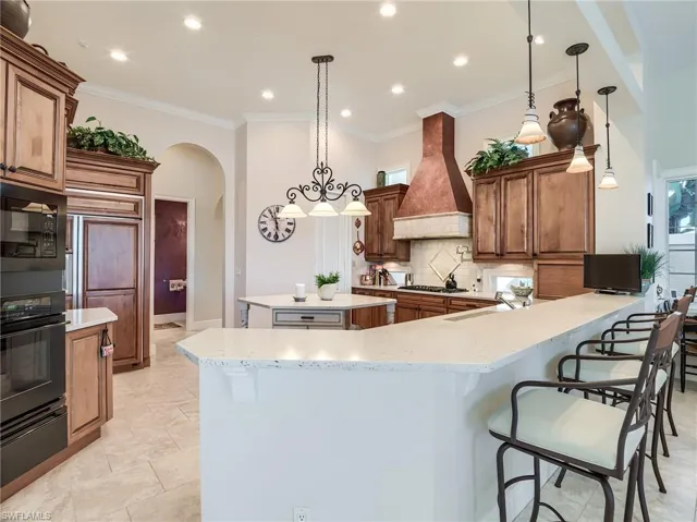 Kitchen with a kitchen island, backsplash, custom exhaust hood, and pendant lighting