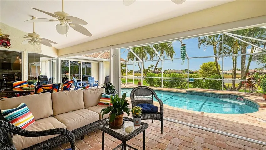 Outdoor pool with an outdoor hangout area, a patio, a ceiling fan, and glass enclosure
