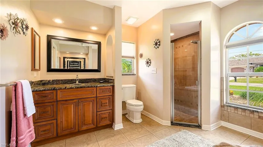 Full bathroom with a shower stall, plenty of natural light, vanity, and toilet