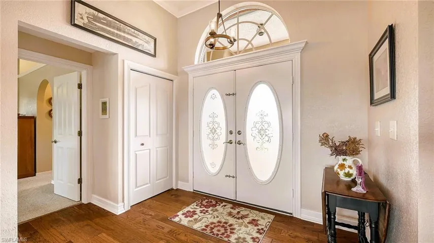 Entryway featuring arched walkways, dark wood-style floors, and baseboards