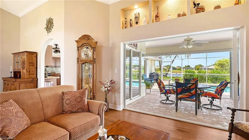 Living room featuring ceiling fan, ornamental molding, a sunroom, plenty of natural light, and wood finished floors
