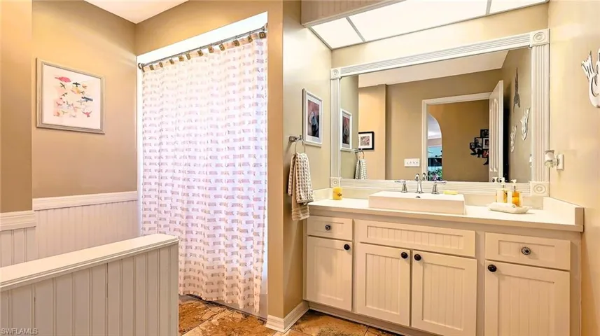 Bathroom featuring a wainscoted wall, vanity, curtained shower, and radiator heating unit
