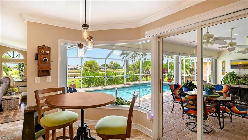 Dining space with a ceiling fan, a sunroom, baseboards, and ornamental molding