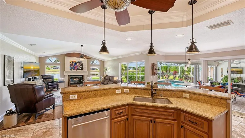 Kitchen featuring ceiling fan, stainless steel dishwasher, a sink, open floor plan, and healthy amount of natural light