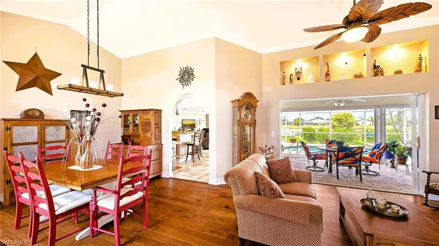 Dining area with a ceiling fan, wood finished floors, high vaulted ceiling, arched walkways, and baseboards