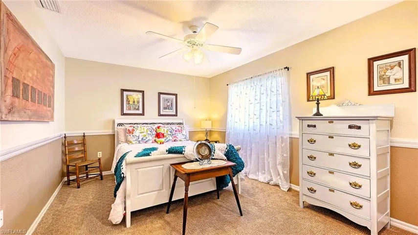 Bedroom with light colored carpet, baseboards, and ceiling fan