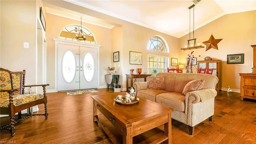 Living area featuring dark wood-type flooring, high vaulted ceiling, french doors, baseboards, and crown molding