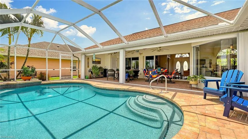Outdoor pool with ceiling fan, a patio area, and glass enclosure