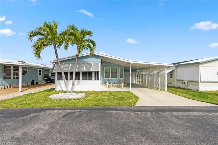 Manufactured / mobile home featuring a front yard and a carport