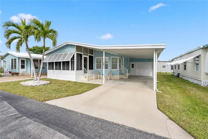 Manufactured / mobile home featuring a carport, a sunroom, and a front lawn