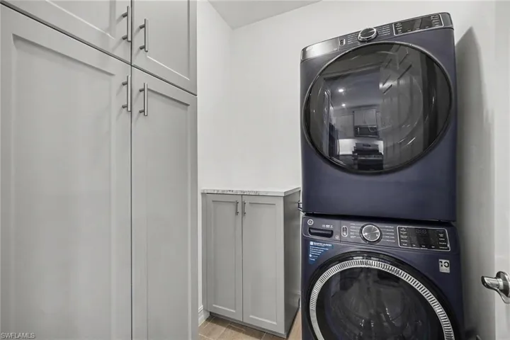 Laundry area featuring light gray cabinetry with brushed nickel hardware, a built-in countertop, and wood-finish flooring