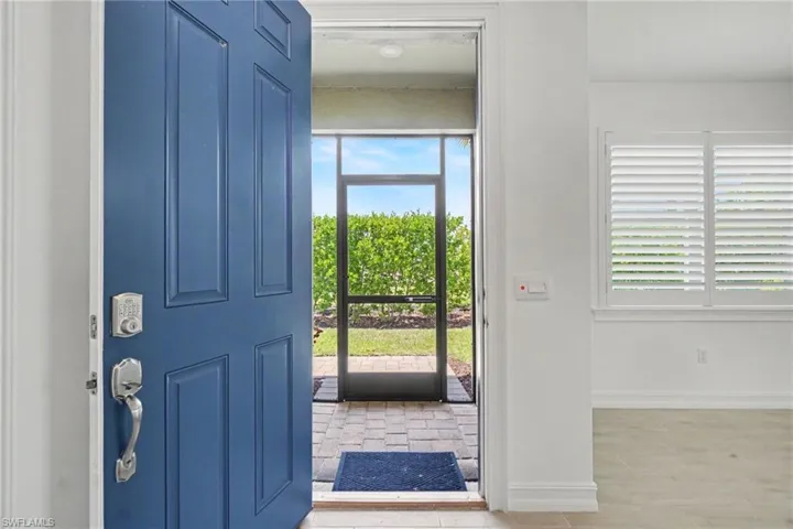 Entrance featuring a paneled blue door with smart lock, screened entry, and brick paver flooring