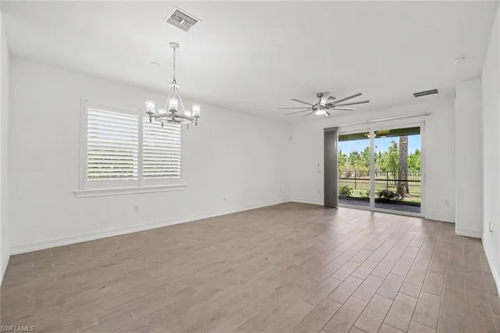 Spacious interior featuring wood-finish flooring, white walls, and a sliding glass door opening to outdoor grounds