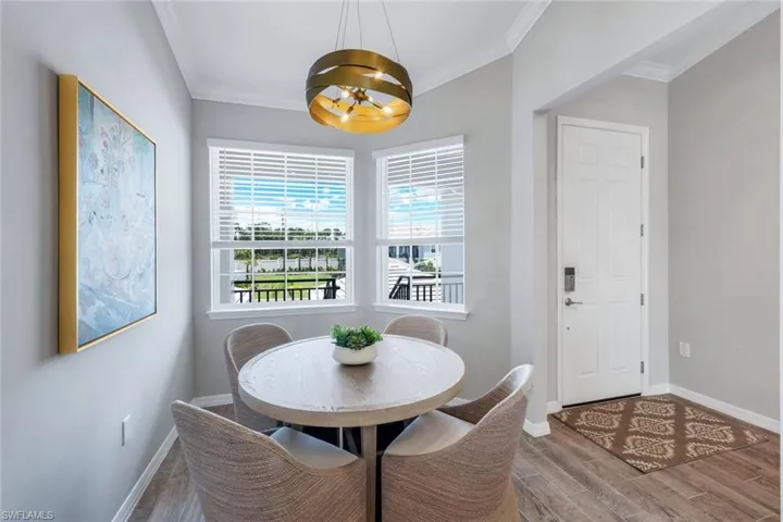 Dining area with a chandelier, wood finished floors, and crown molding