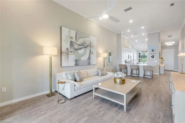 Living room with light wood-style floors, ornamental molding, ceiling fan, and recessed lighting